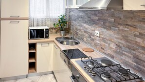 Eine kleine Küche mit Mikrowelle, Spüle, Herd und einer Steinwand.
