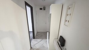 Ein Flur mit einer weißen Tür, einem weißen Kleiderschrank und einem kleinen, schwarzen Gerät auf einer weißen Fläche.