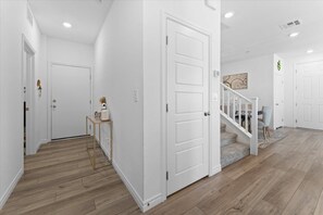 Ein Korridor mit weißen Wänden, Holzboden und einer geschlossenen Tür.