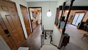 A hallway with wooden flooring, a staircase, a dining area with a table and chairs, and a kitchen in the background. - Your FIFA World Cup Base Camp-6 miles from the stadium (Raytown)