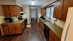 A kitchen with wooden cabinets, a dishwasher, and a countertop. - Your FIFA World Cup Base Camp-6 miles from the stadium (Raytown)