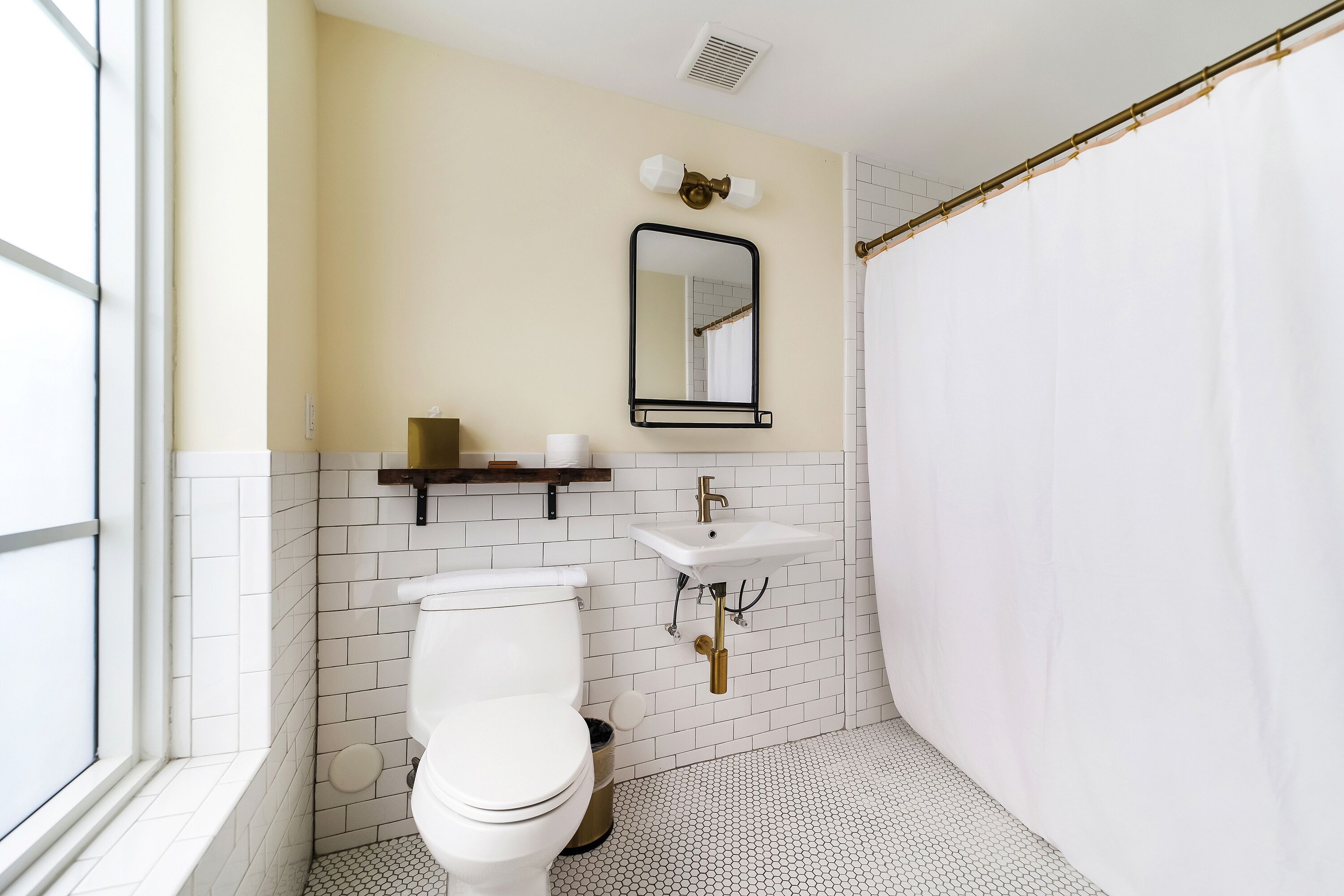 Une salle de bain équipée de toilettes, d’un lavabo, d’un miroir et d’un rideau de douche.