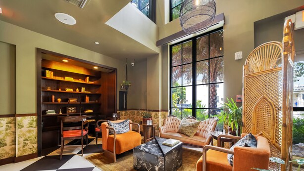 Uma sala de estar ampla com piso xadrez, um conjunto de sofás, uma mesa de centro e uma estante de livros.