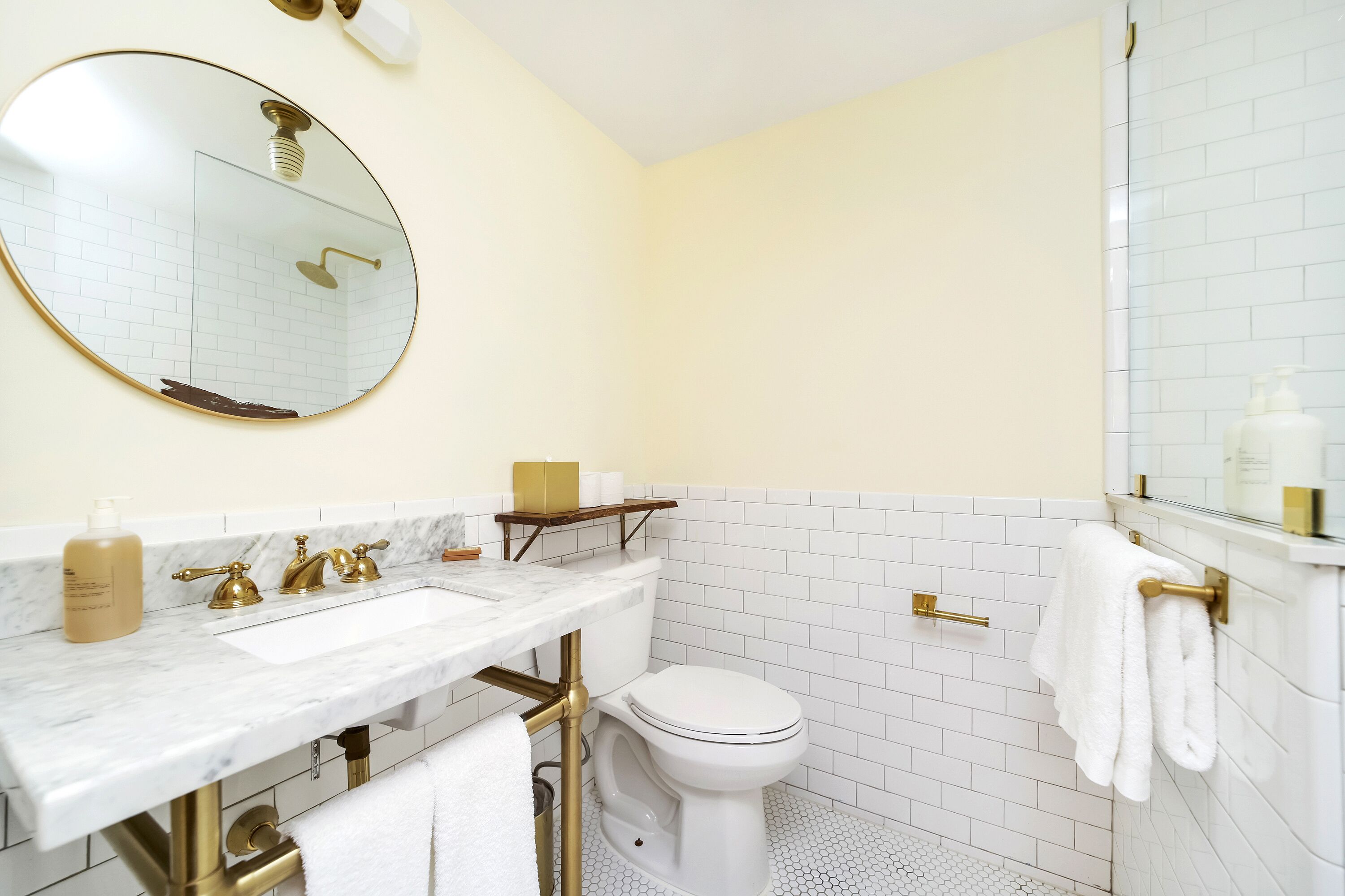 A bathroom with a white toilet, a sink with gold fixtures, and a mirror.