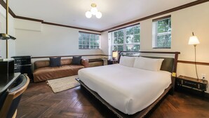 Quarto de hotel com cama grande, sofá, escrivaninha e abajur.