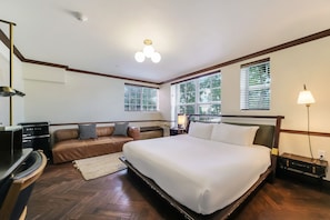 Habitación de hotel con una cama grande, un sofá, un escritorio y una lámpara.