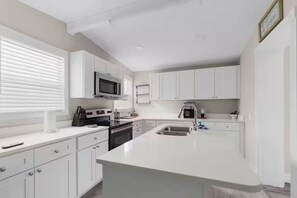 A modern kitchen with white cabinetry, a built-in microwave, a stove, and a sink. - Welcome to Serene Sunshine Retreat Spring Hill, FL (Spring Hill)