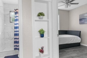Een slaapkamer met een bed, een plafondventilator en een aan de muur hangend schilderij.