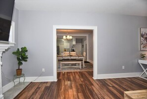A room with wooden flooring, a dining table with chairs, a potted plant, and a painting on the wall. - NEW- LUXURY CHERRY ST -SHOP DINE -2 BEDROOM HOUSE-HOSPITALS-RT 66--DOWNTOWN (TULSA)