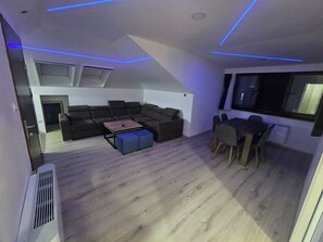 Une chambre moderne de style loft, dotée d’un canapé d’angle, d’une table à manger avec des chaises et d’une grande fenêtre.