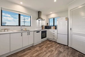Une cuisine moderne avec des meubles blancs, un lave-vaisselle, un four et un réfrigérateur.