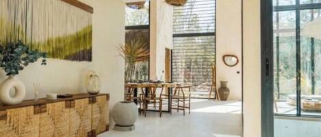 A modern interior with a wooden console, a dining area, and large windows.