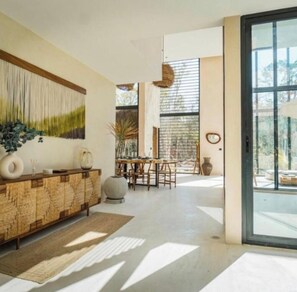 A modern interior with a wooden console, a dining area, and large windows. - Luxury Jungle Villa | Pool, Sauna, Rooftop (Tulum)