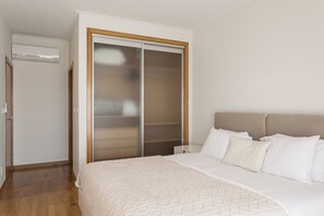 A bedroom with a bed, a wardrobe, and an air conditioning unit. - Colinas Premium 3BR - Three Bedroom Apartment, Sleeps 5 (Sintra)