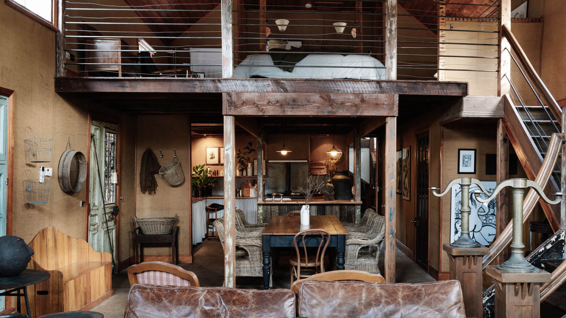 A rustic interior with a dining area, wooden furniture, and a staircase.