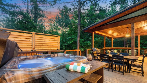 A hot tub on a wooden deck with a covered seating area and a view of trees. - Retreat w/ Sauna, Hot Tub, Games & Fenced Dog Yard! (Broken Bow)