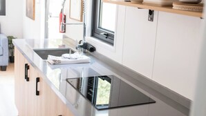 Una cocina moderna con encimera de acero inoxidable, armarios de madera, horno empotrado y una ventana sobre el fregadero.