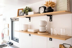 Una cocina con estantes de madera que contienen utensilios de cocina, un reloj y objetos decorativos.