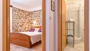 Een slaapkamer met een stenen muur, een houten bed en een douche met een glazen deur.