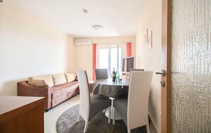 Une pièce comprenant un canapé, une table à manger avec des chaises, un téléviseur et une porte.