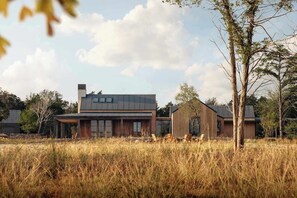 Een modern huis met een groot raam, een schoorsteen en een houten terras.
