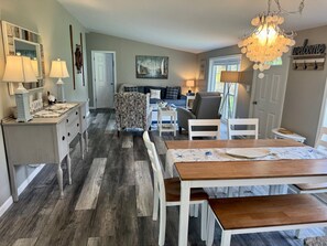 A dining area with a wooden table and benches, a kitchen area with a counter and cabinets, and a living room with a sofa and a coffee table.