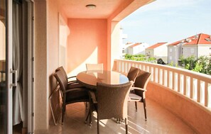 Un balcon avec une table ronde et quatre chaises, une balustrade blanche et une vue sur des bâtiments aux toits rouges.