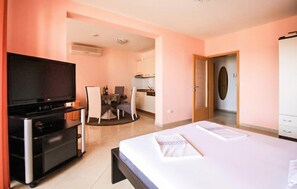 Habitació d'hotel amb llit, televisió, escriptori i petita cuina.