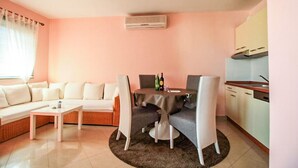 Un salon comprenant un canapé, une table basse, une table à manger avec des chaises, ainsi qu’un coin cuisine avec des placards et une cuisinière.