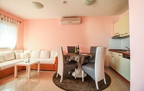Un saló amb un sofà, una taula de centre, una taula de dinar amb cadires, i una zona de cuina amb armaris i una cuina.