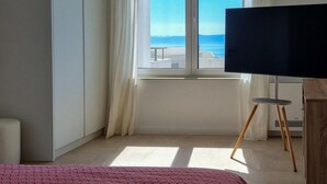 A bedroom with a large window, a bed, a TV, and a small stool. - Beautiful home in Makarska (Makarska)
