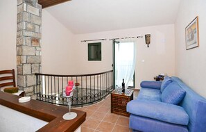 A living room with a stone pillar, a blue sofa, a wooden table, and a staircase with a metal railing.