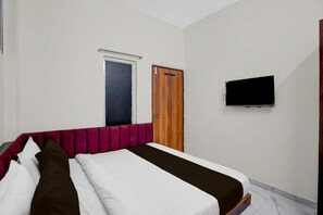 A bedroom with a bed, a television, a door, and a window. - Hotel Day & Night stay (Bhopal)
