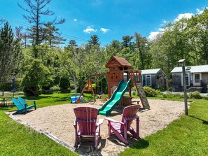 Un parque infantil con tobogán, columpios y estructura para escalar.