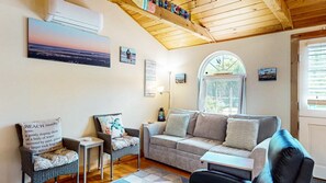 A cozy living room with a sofa, two chairs, a small table, and a window with a view. - Coastal Shorelands Retreat + Walk-to-Beach Access and Pool (Kennebunk)
