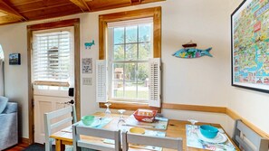 A cozy room with a wooden ceiling, a dining table with chairs, a window with blinds, and a wall with a map. - Coastal Shorelands Retreat + Walk-to-Beach Access and Pool (Kennebunk)