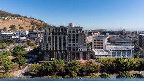 Ein mehrstöckiges Hotel mit Innenhof, umgeben von städtischen Gebäuden und einer hügeligen Landschaft.