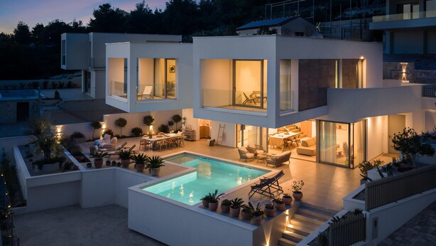 Uma casa moderna de vários andares com piscina, área de estar ao ar livre e um pátio bem iluminado.