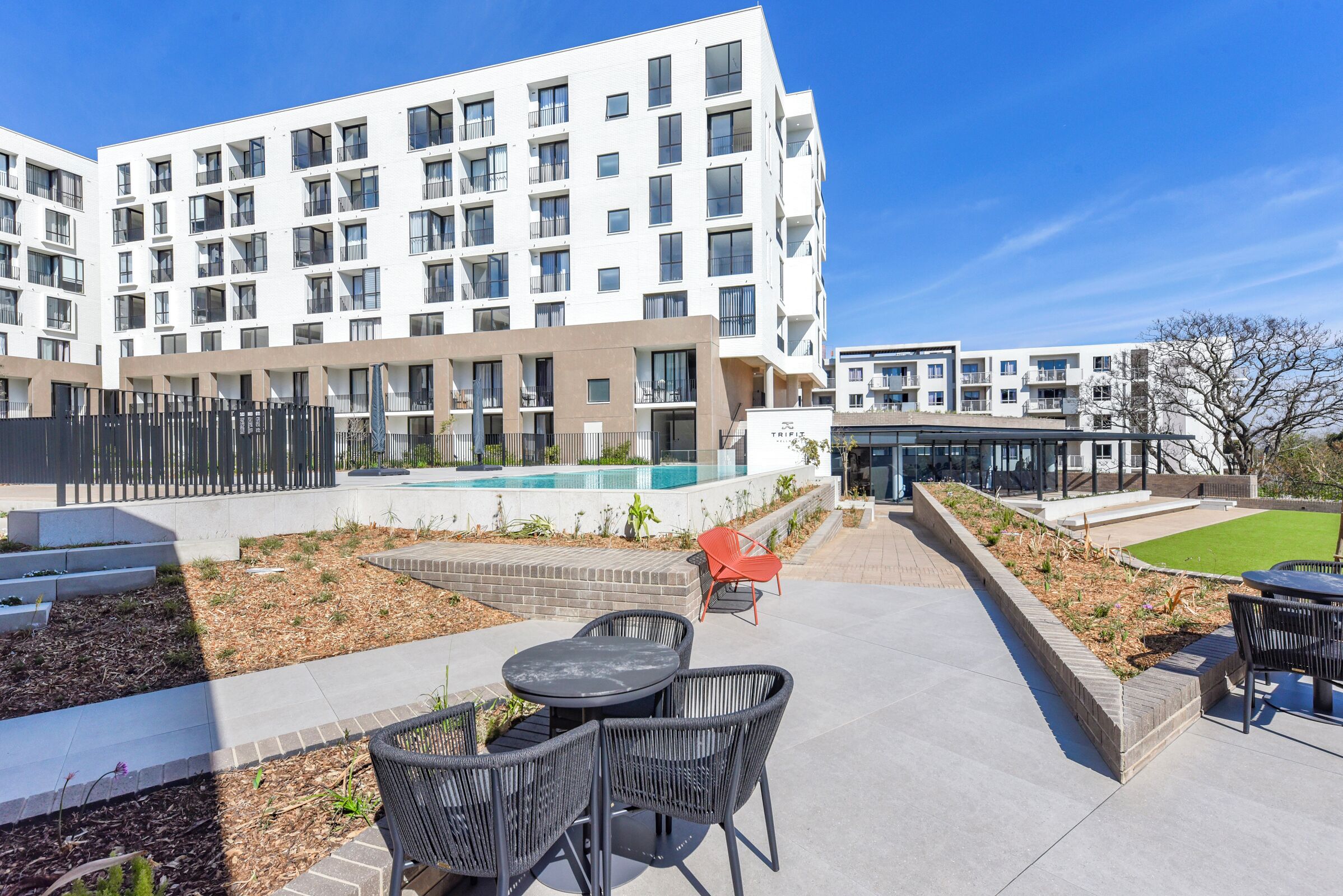 Un immeuble d’appartements moderne doté d’une piscine et d’un espace extérieur aménagé pour se détendre.