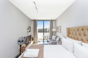 Ein Hotelzimmer mit Bett, Sitzecke, Balkon und Blick auf die Stadt.