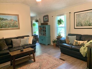 A living room with two leather sofas, a wooden coffee table, a patterned rug, a teal cabinet, and framed artwork on the walls. - PRIVATE retreat at the 
“island time cottage”
 on Daufuskie Island (Daufuskie Island)