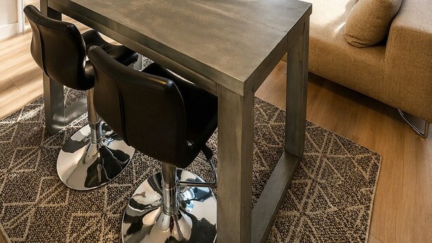 Een moderne woonkamer met een eettafel, stoelen, een bank, een televisie en grote ramen.