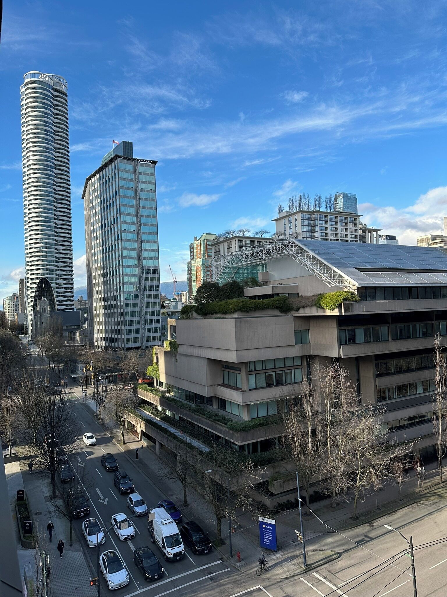 A cityscape with modern buildings, a parking lot, and a clear sky.