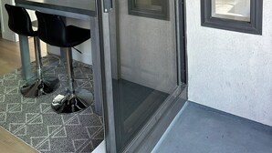 Een kamer met een schuifdeur van glas, een eettafel met stoelen en een klein raam.