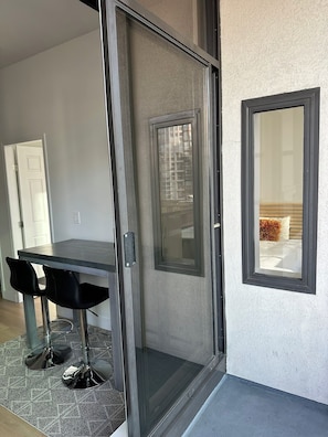 A room with a sliding glass door, a dining table with chairs, and a small window. - Curated Comfort: 1BR Loft | King+Double Beds (Vancouver)