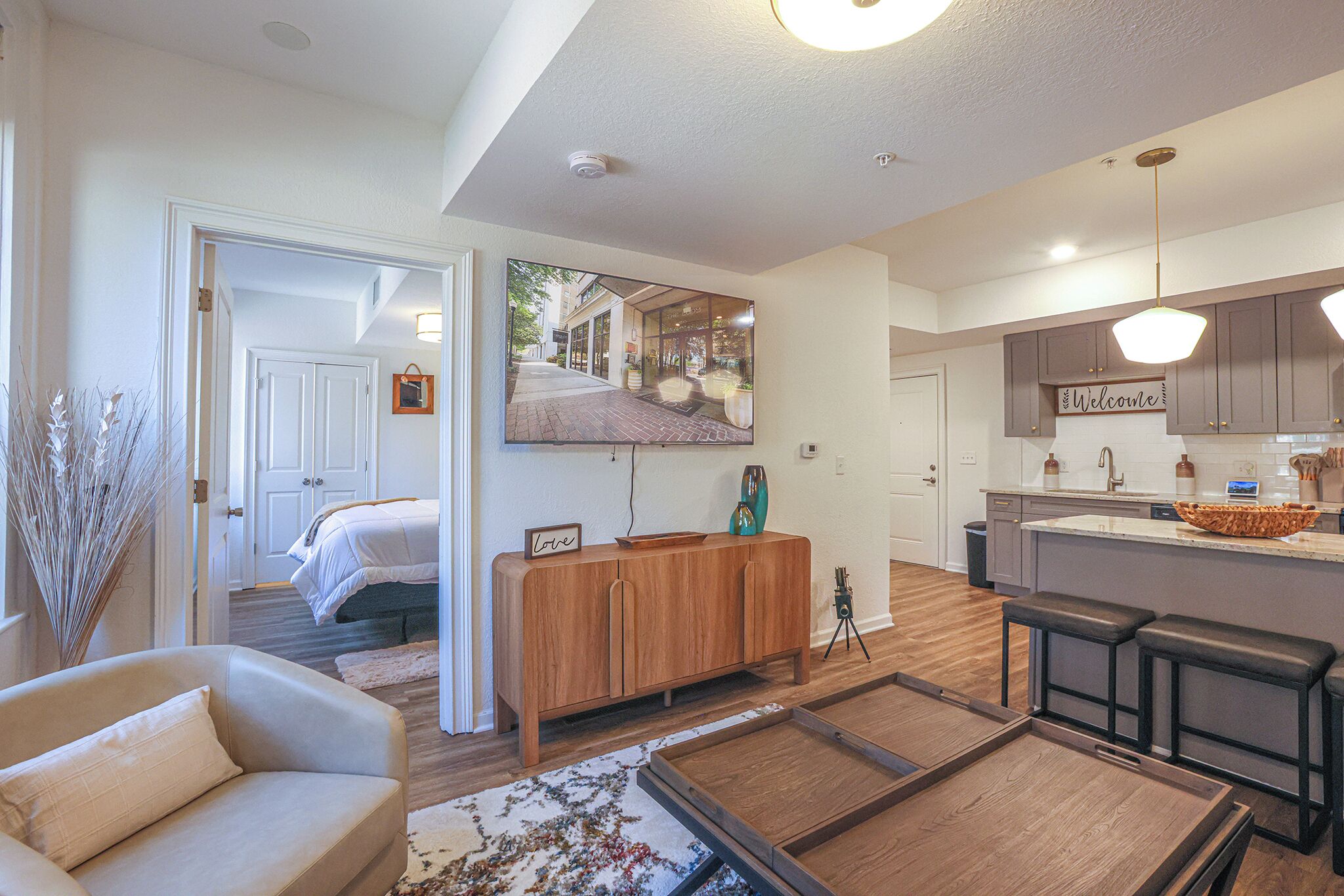 A modern kitchen with a wooden island, a dining area with a bench, and a living room with a sofa.