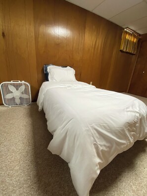 A bed with white bedding in a room with wooden walls and a ceiling fan. - Under The Cherry Boon: A Traverse City Dream (Traverse City)