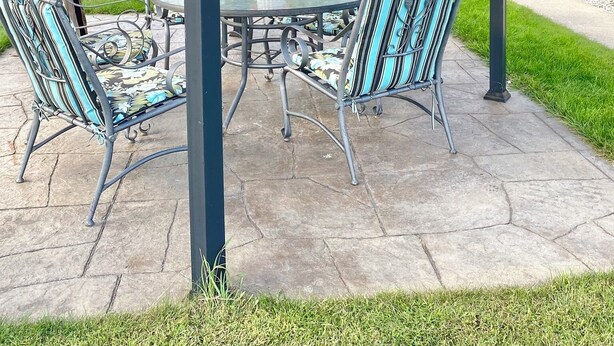Overdekt terras met een tafel, stoelen, een bloevas en uitzicht op een woonstraat.