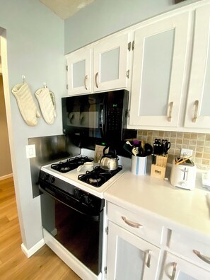 A kitchen with white cabinets, a black stove, and a microwave. - Under The Cherry Boon: A Traverse City Dream (Traverse City)