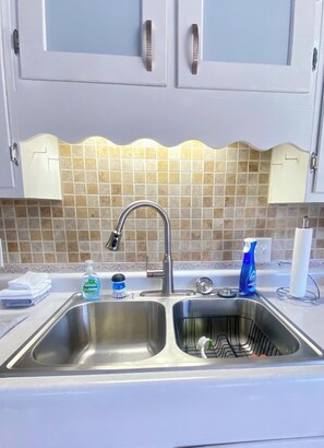 A kitchen with a double sink, stainless steel faucet, and tiled backsplash. - Under The Cherry Boon: A Traverse City Dream (Traverse City)
